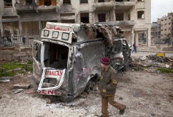 Un joven sirio camina junto a una ambulancia destruida en el distrito de Saif al-Dawla en la ciudad norteña de Aleppo, zona que ha quedado devastada por la guerra, el 12 de enero de 2013. © 2013 JM López / AFP / Getty Images
